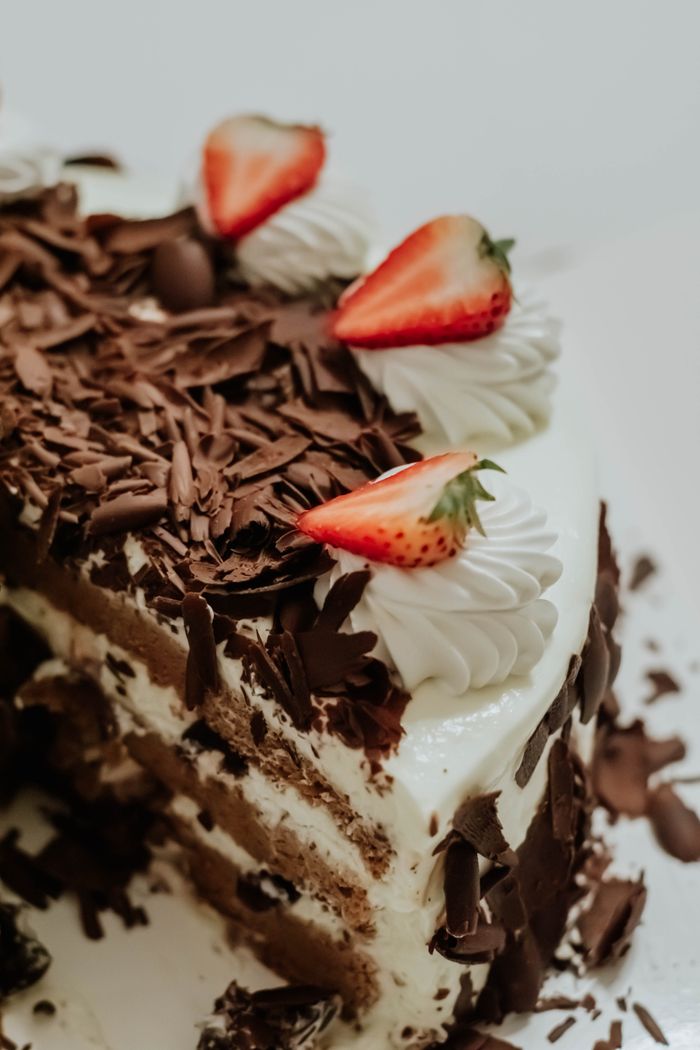About Indulgent chocolate cake topped with strawberries and cream, perfect for dessert lovers.