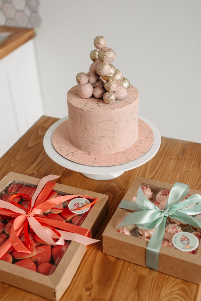Home A beautifully decorated pink cake with gift boxes, perfect for celebrations.